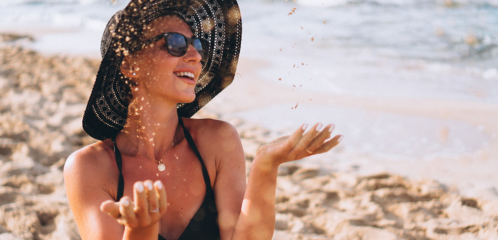 Beautiful woman sitting on sand by the ocean